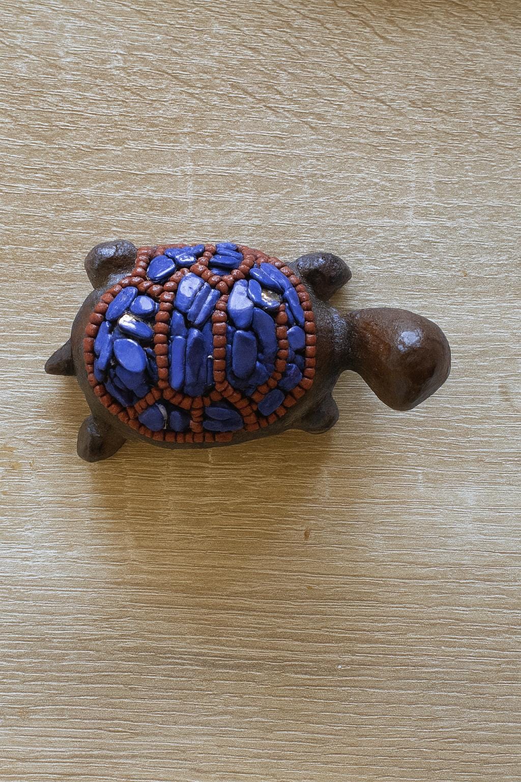 Decorative turtle figurine with blue and brown design on a wooden surface