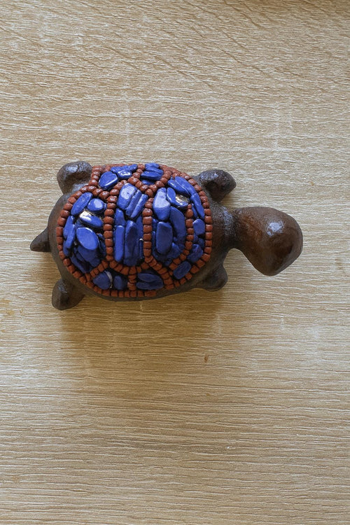 Decorative turtle figurine with blue and brown design on a wooden surface