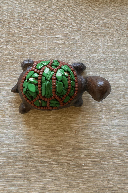 Decorative turtle figurine with green shell on a wooden surface