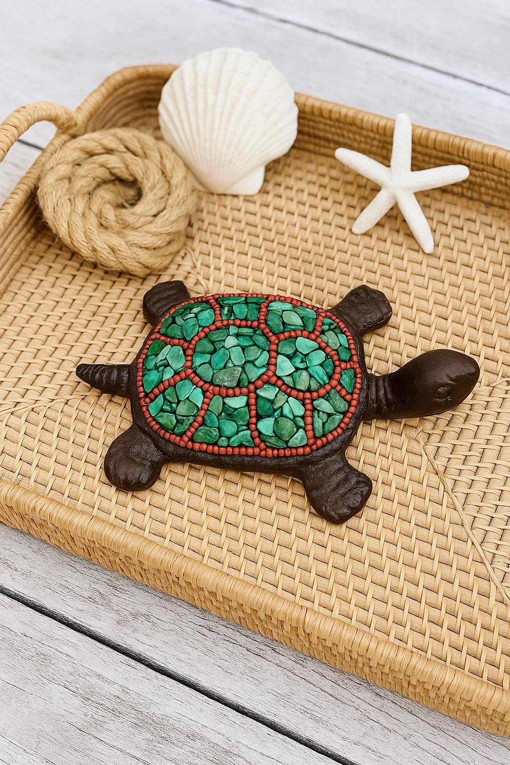 Decorative turtle with green shell on a woven tray with shell and starfish