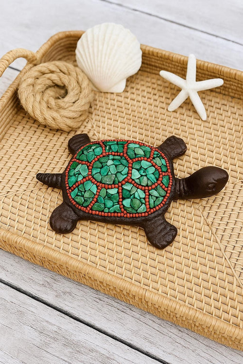 Decorative turtle with green shell on a woven tray with shell and starfish