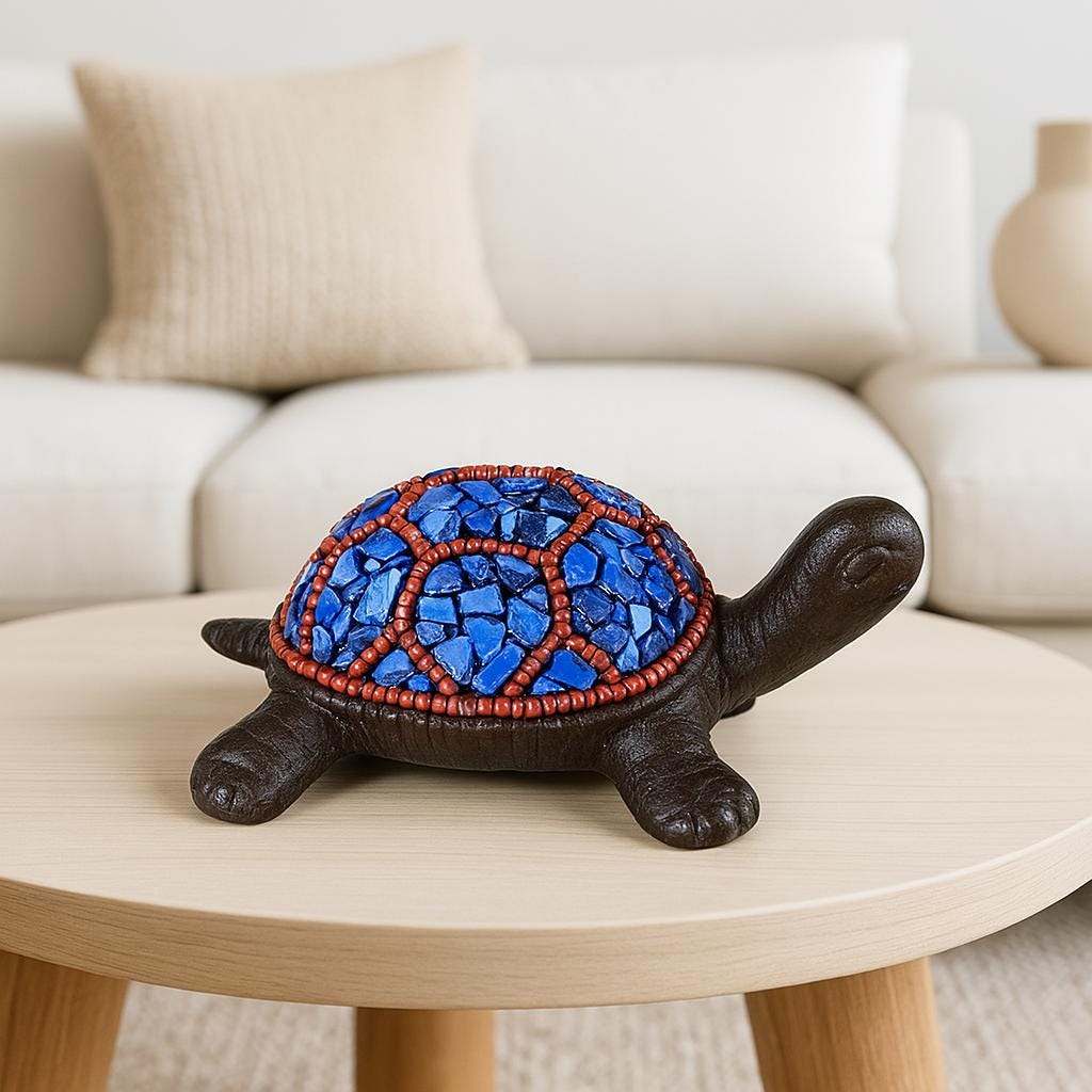 Decorative turtle figurine with blue and red mosaic shell on a wooden table.